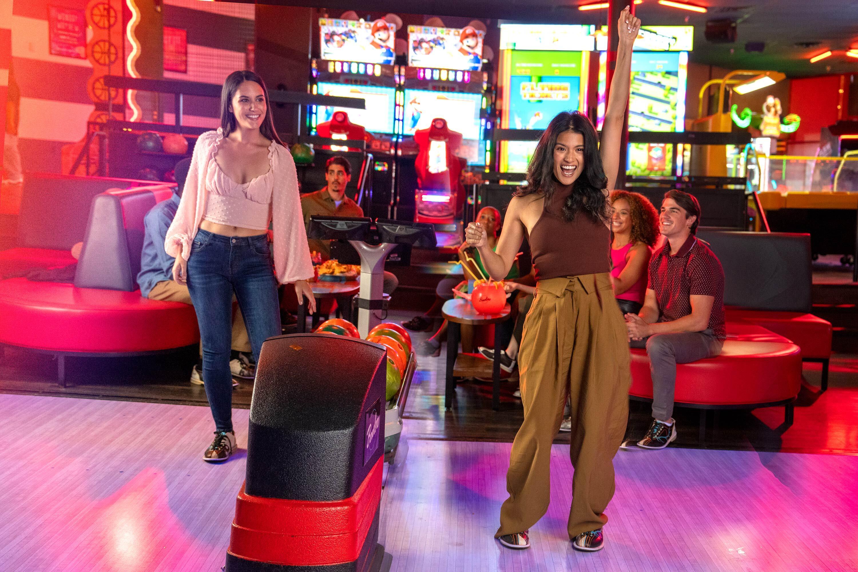 Two girls laughing and having fun while bowling. 