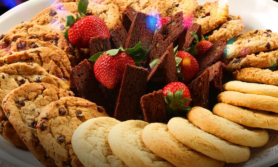 A plate of dessert including cookies, brownies and strawberries. 