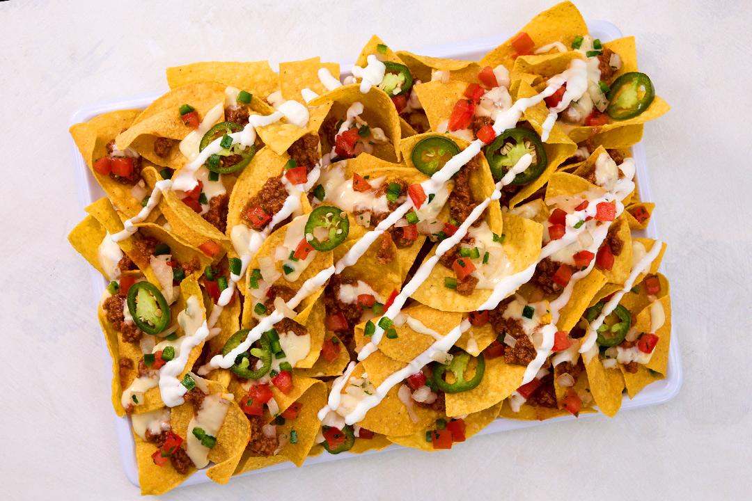 Nachos on a plate drizzled with toppings.