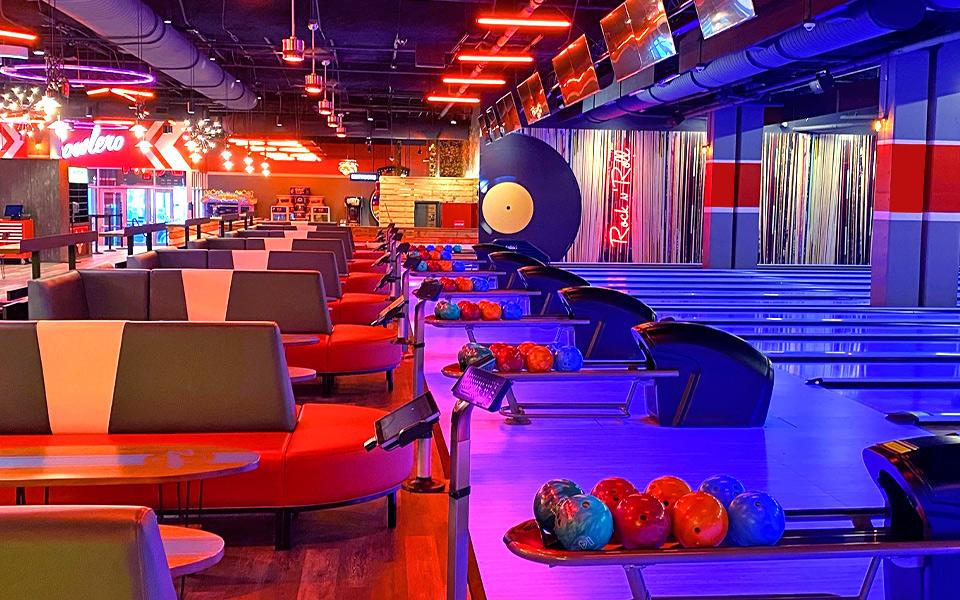 Row of colorfully lit bowling lanes and ball returns