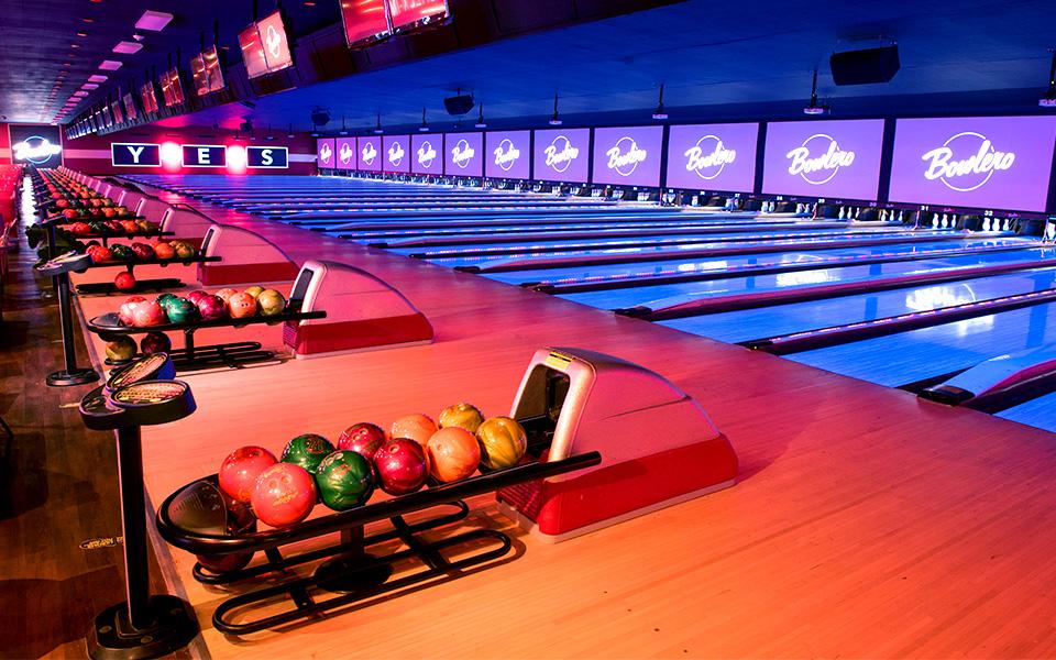 Many bowling lanes with bowling balls lined up on the returns