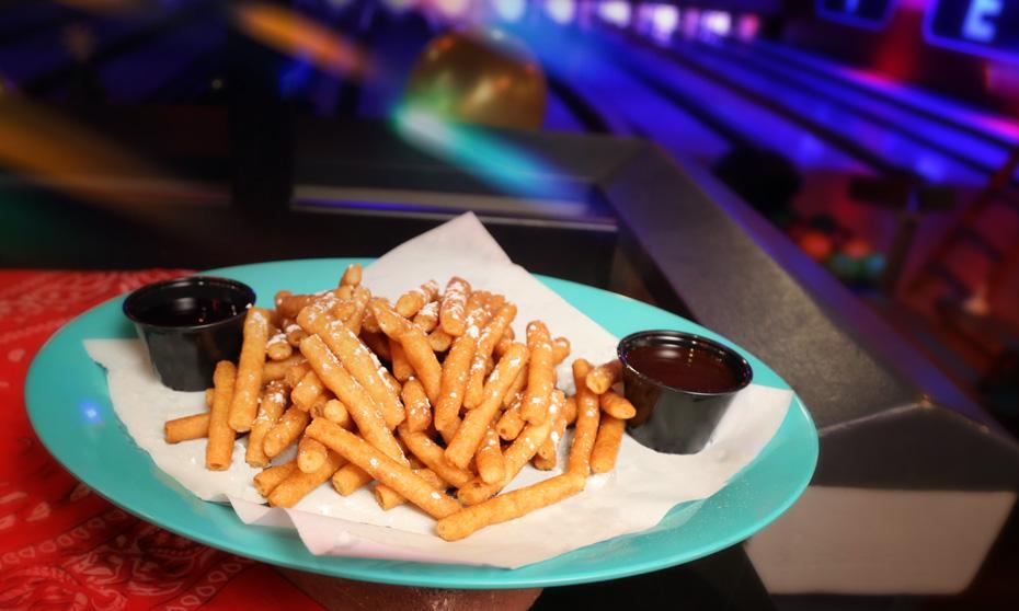 Funnel cake cries set up on a plate with lanes in the background. 