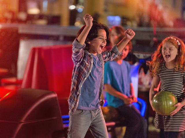 Kids celebrating as one of the kids got a strike while bowling.